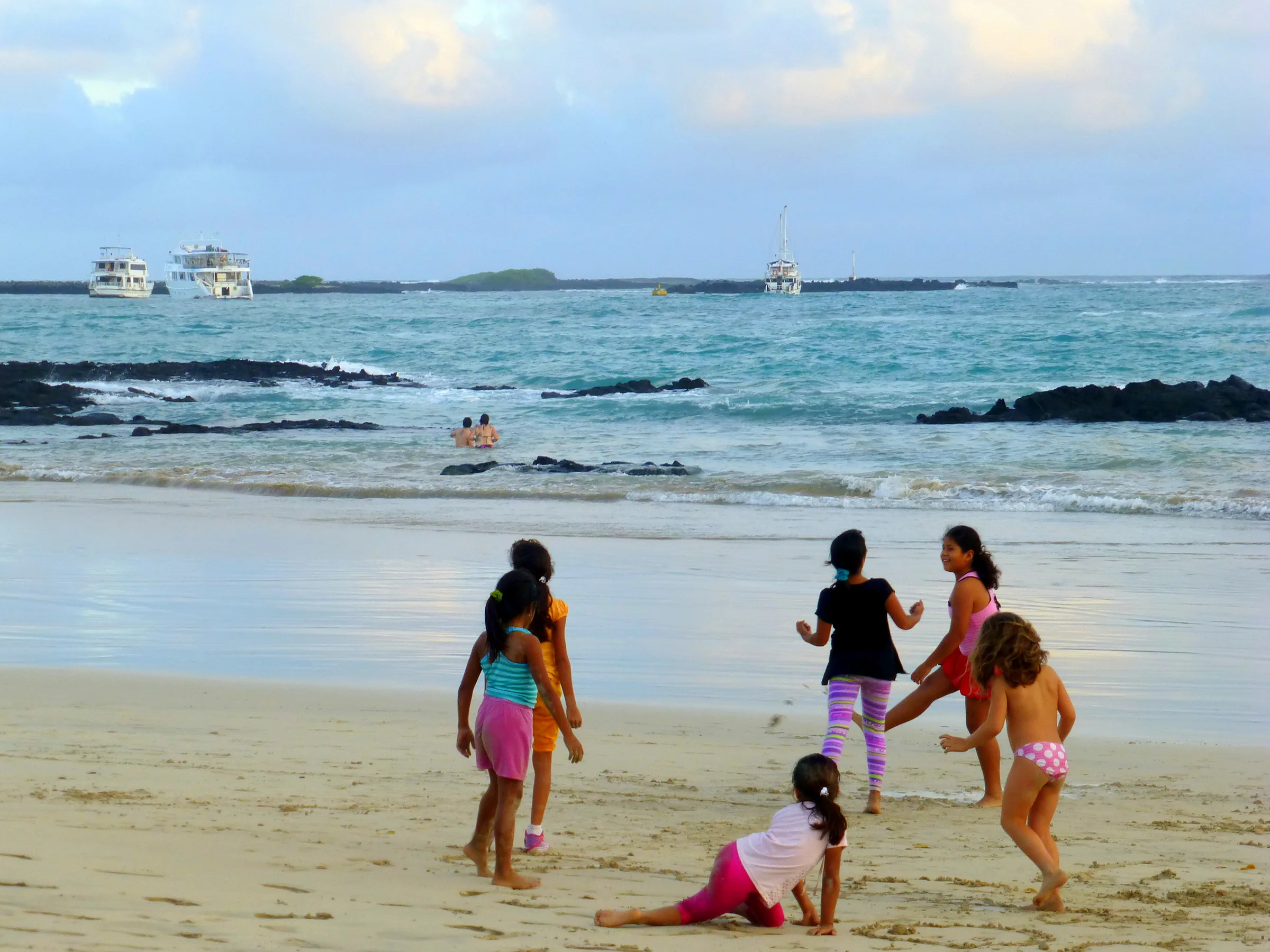 Children play & swim on the beach in front of the Lodge. Three cruise boats are moored in the distance.
