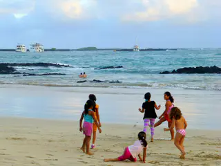 Children play & swim on the beach in front of the Lodge.  Three cruise boats are moored in the distance.