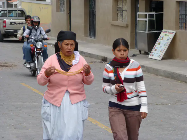 Woman in traditional dress and her young daughter, perhaps, in modern apparel carrying a cell phone.