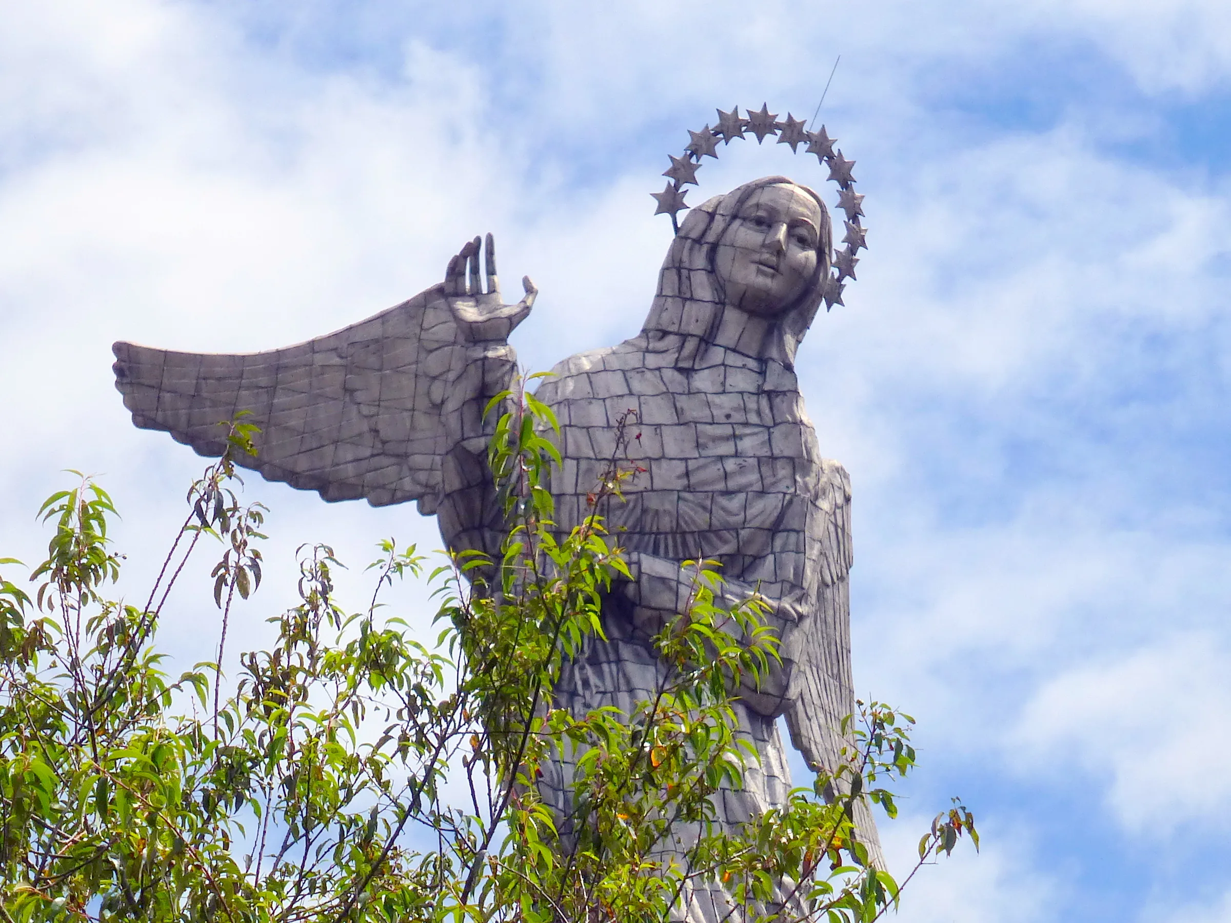 El Panecillo. On this mountain, an angel overlooks the City of Quito. Per Wikipedia, "In 1976, the Spanish artist Agustín de la Herrán Matorras was commissioned by the religious order of the Oblates to build a 45-metre-tall aluminum monument of a madonna which was assembled on a high pedestal on the top of Panecillo. It is made of seven thousand pieces of aluminium. ...The virgin stands on top of a globe and is stepping on a snake, which is a classic madonna iconography. Less traditional are the wings. Locals claim that she is the only one in the world with wings like an angel. The monument was inspired by the famous "Virgen de Quito" (Quito's Madonna) also known as "the dancer" sculpted by Bernardo de Legarda in 1734, which now decorates the main altar at the Church of St. Francis. ...According to a bronze placard affixed to the monument, the woman represented by the statue is the Woman of the Apocalypse, as described in the Book of Revelation (Revelation 12:1–18)."