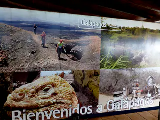 Airport sign - Welcome to the Galapagos. Photos include the volcano hike on Isabela Island, a land iguana's head, and post office bay in Floreana.