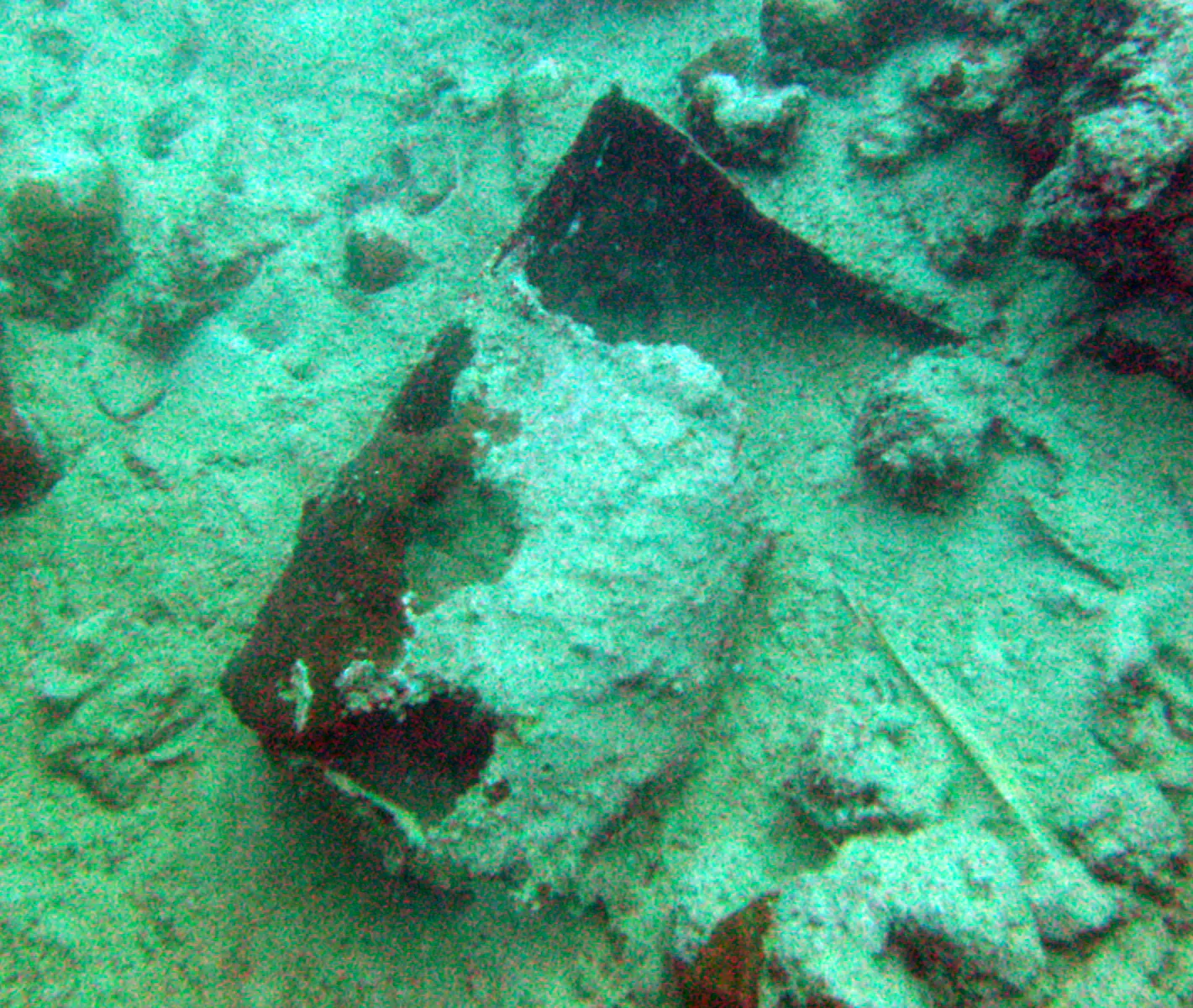 A disintegrating oil drum lies in the sand beside the wreck.