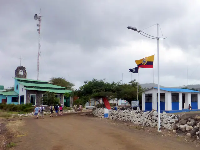 Floreana - Puerto Velasco Ibarra Harbor.  Church on let and Ecuadorian Naval Post on right.  Group is walking to the Chiba.
