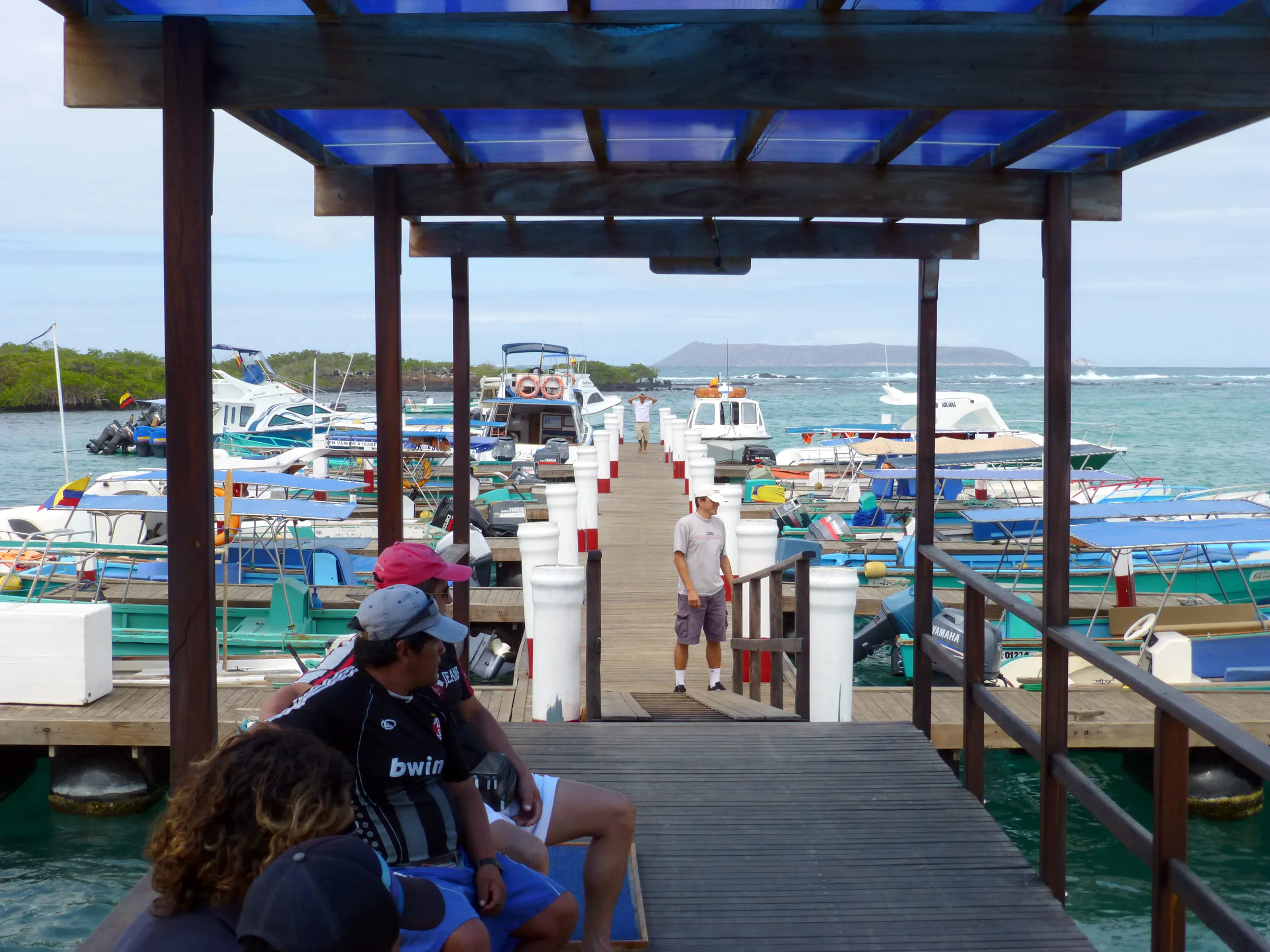 The ferry boat landing dock at Puerto Villamil. "Puerto Villamil is a small port village located on the southeastern edge of Isla Isabela in the Galapagos Islands. Of the 2,200 people who live on Isabela, the majority live in Puerto Villamil. ... On the northern edge of town near the dock are a series of small islets including one known as Las Tintoreras where a colony of white tip sharks can often be seen resting in the lava channel." Wikipedia.